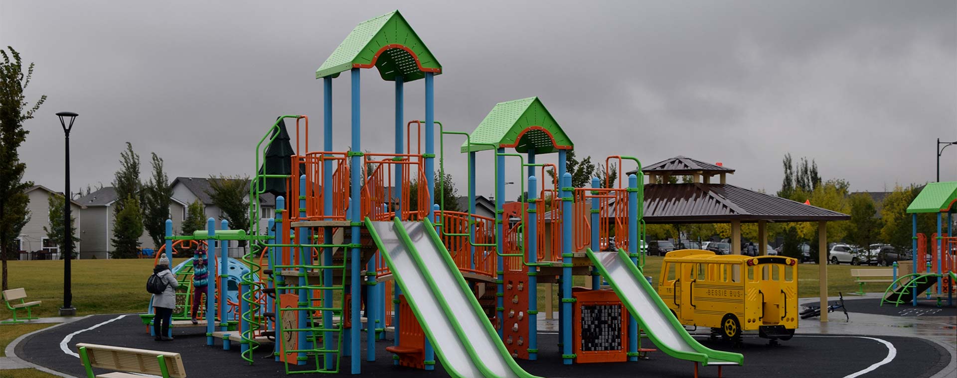 A large playground, with two slides in West Edmonton. The playground is red, blue, green and yellow. There is a gazebo just behind the playground