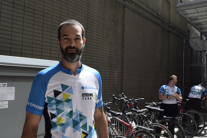Sean standing in front of a bike rack wearing a Team Alberta Blue Cross cycling shirt