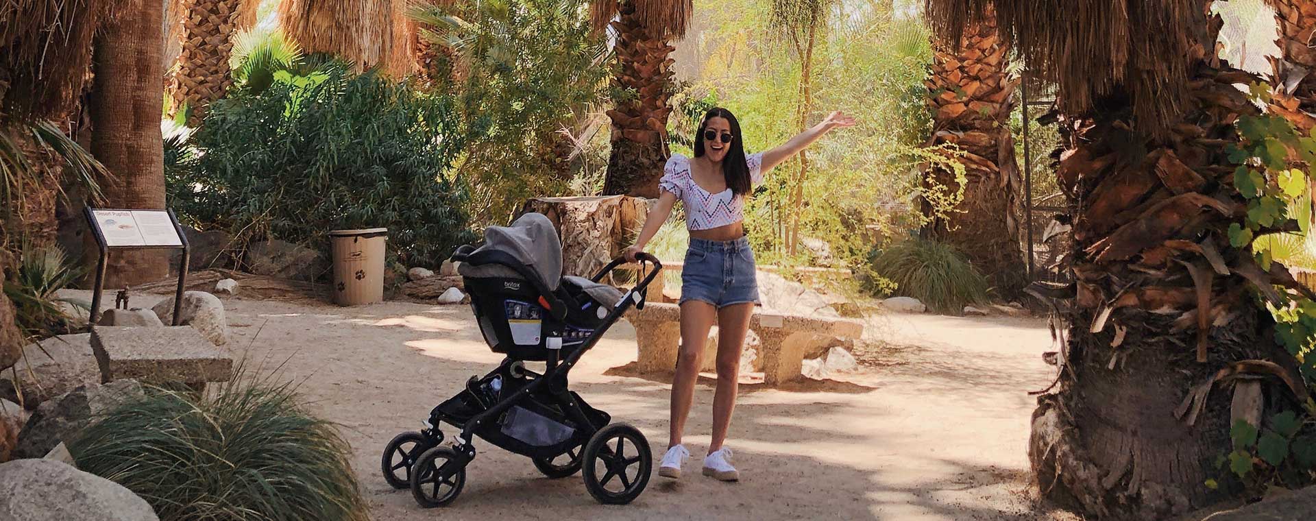 Lindsay Smith standing amid tropical trees, with a stroller beside her.