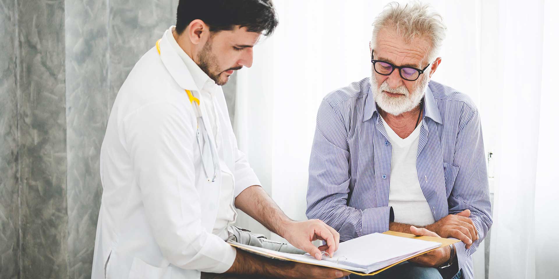 A doctor is reviewing patient's chart with a senior patient.