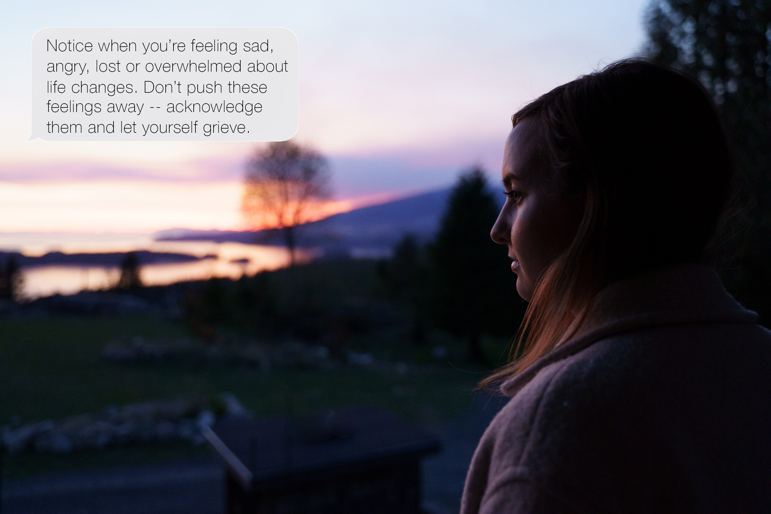 Woman looking out onto river valley at dusk.