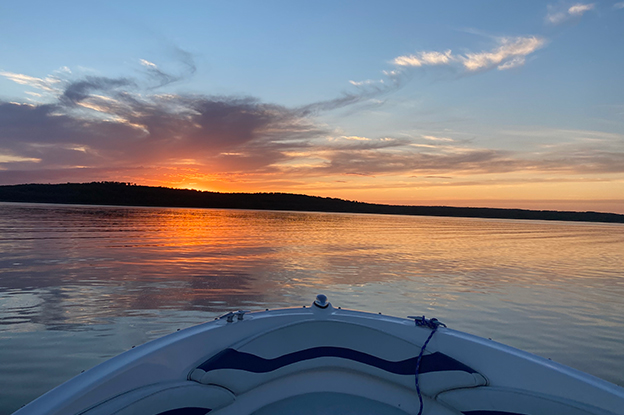 A boat on a clam White Bear Lake during a sunset.