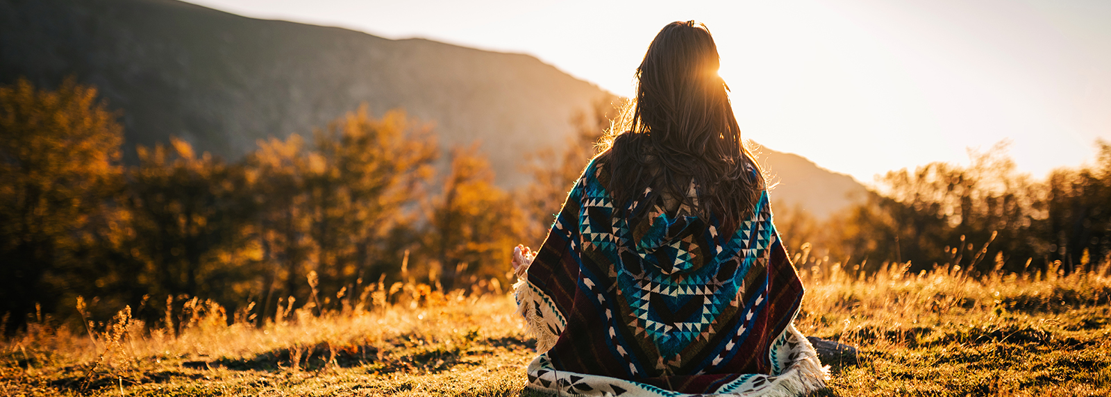 Young boho woman in the nature. Young woman watching the sunrise and meditating in the nature.