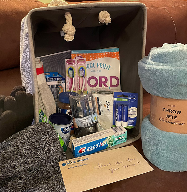 A gift basket including hygiene products, tea, socks, gloves, hat and a blanket.