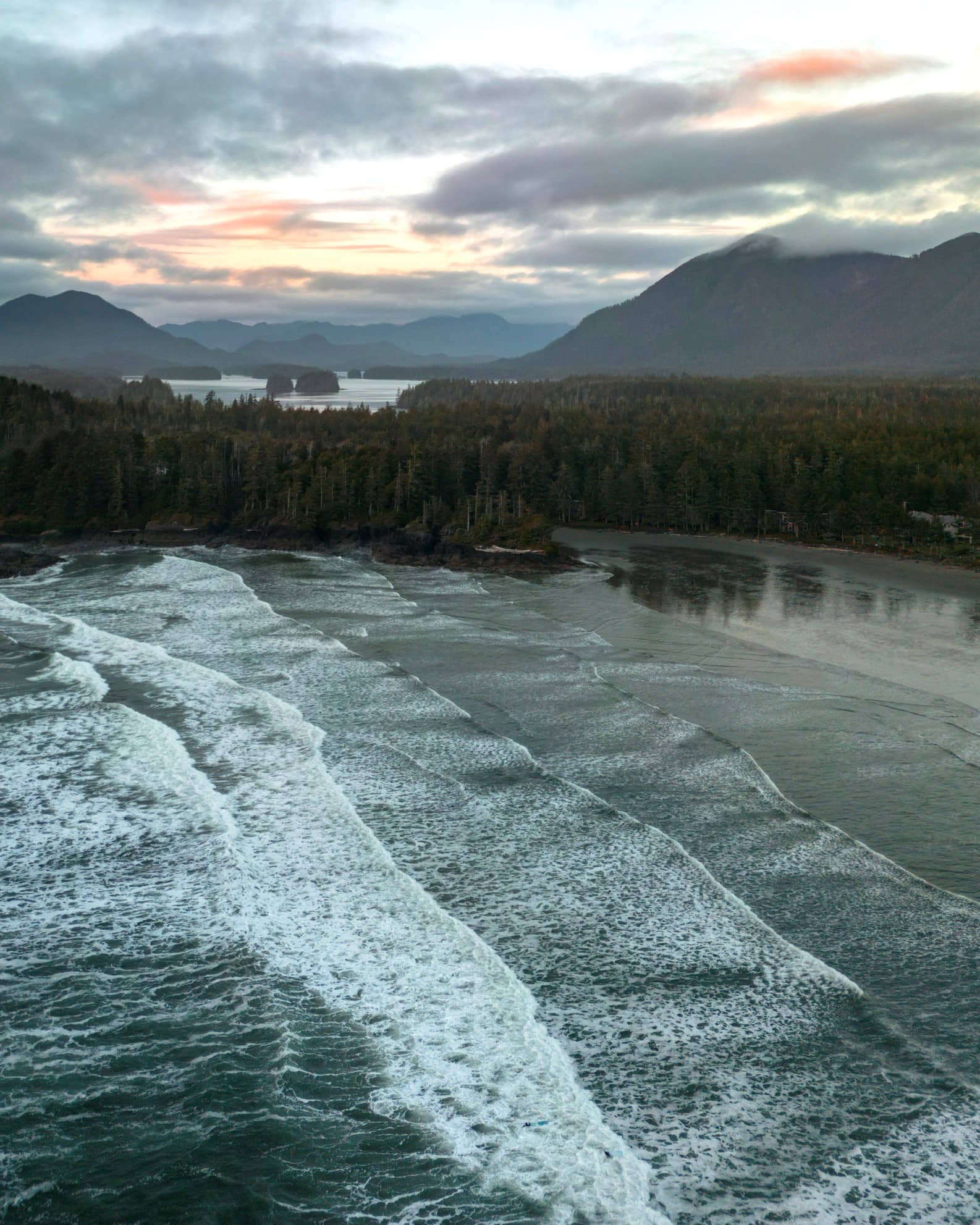 Gentle waves on a beach surrounded by mountains.