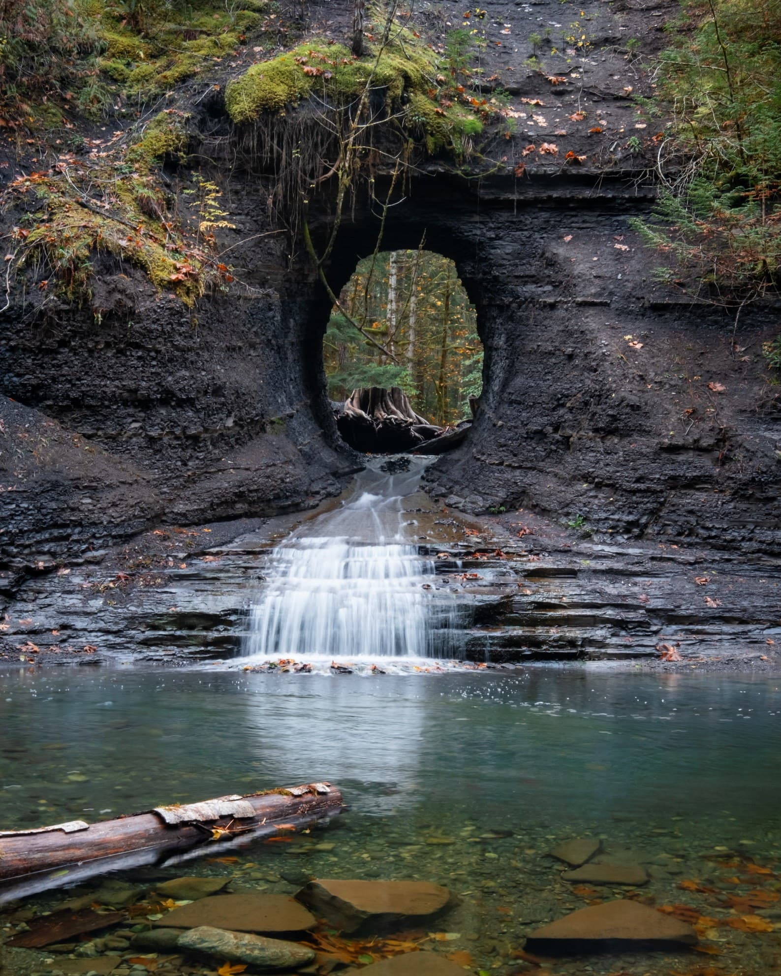 A small waterfall flowing through a hole in the rock face.