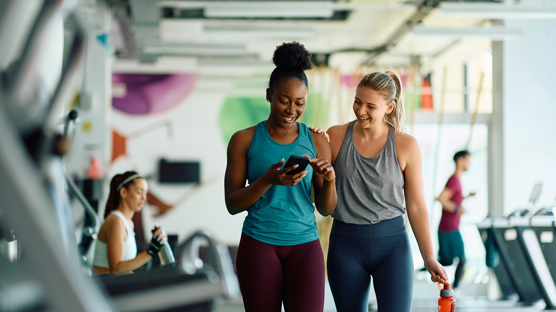 Young female athletes using mobile phone while exercising in a gym.