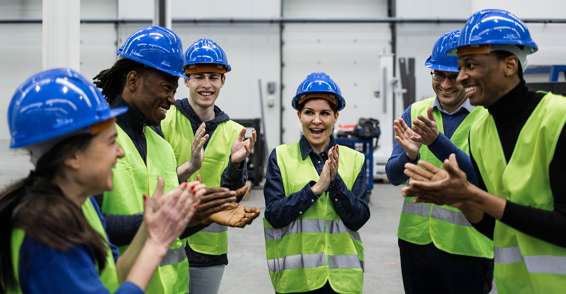 Team members smiling together, wearing safety vests and hard hats.